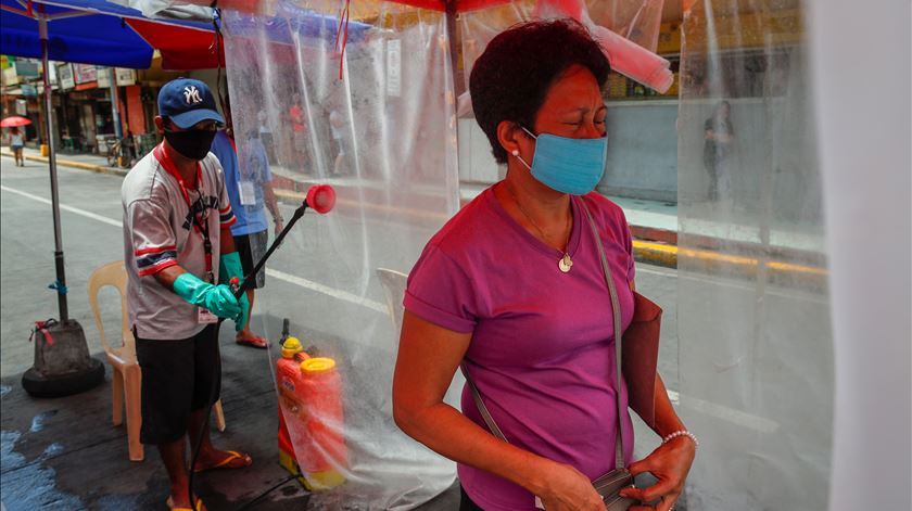 Manila, Filipinas. Uma mulher é pulverizada com desinfetante, à entrada de um mercado público. Foto: Mark R. Cristino/EPA