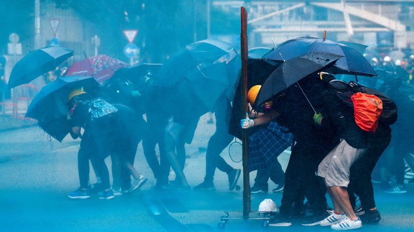Manifestantes protegem-se dos canhões de água da polícia. Foto: Athit Perawongmetha/Reuters