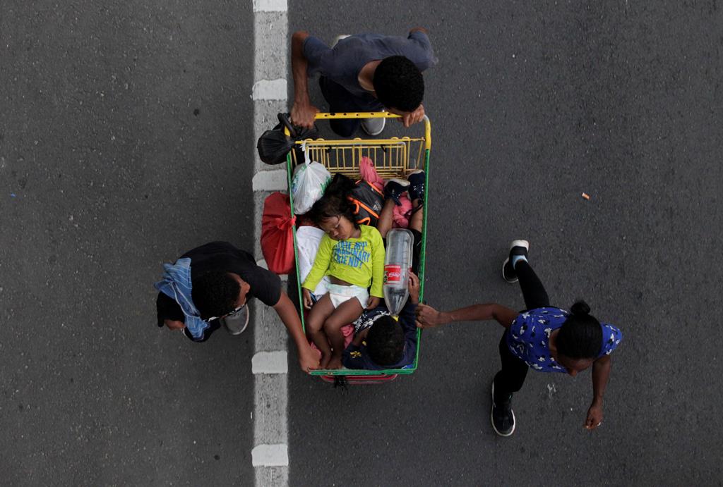 Imigrantes irregulares transportam crianças num carrinho de surpermercado durante a "caravana humana", no México. Foto: Daniel Becerri/Reuters