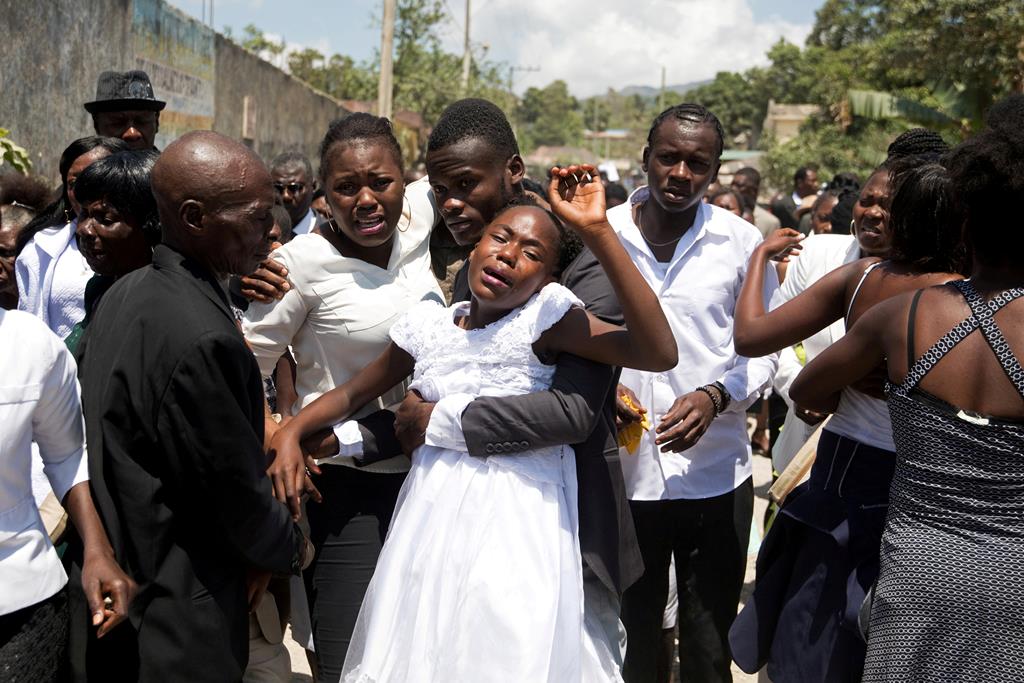 Irmãos Rode e Rodelin, de 13 e 18 anos, durante um funeral em Plaisance, no Haiti. Apesar de grande parte da população viver em situação de pobreza extrema, os rituais fúnebres são eventos em que as famílias gastam grande parte das suas poupanças. Foto: Valerie Baeriswyl/Reuters