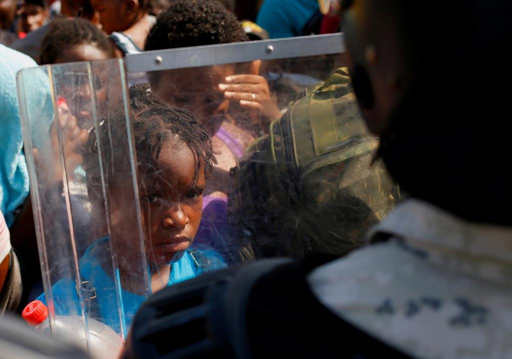 Uma criança encara um membro da Guarda Nacional do México, enquanto aguarda junto a uma multidão para entrar num autocarro, depois de conseguir um visto. Foto: Jose Luis Gonzalez/Reuters