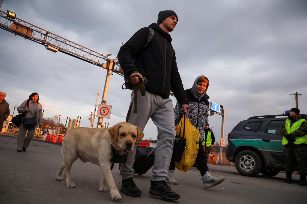 Um homem caminha com uma criança e o seu cão, junto a um posto fronteiriço entre a Polónia e a Ucrânia, em Medyka, Polónia. (26 de fevereiro de 2022) Foto: Kacper Pempel/Reuters