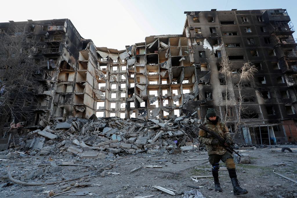 Membro das tropas pró-russas à frente de um edifício de apartamentos destruído em Mariupol. Foto: Alexander Ermochenko/Reuters