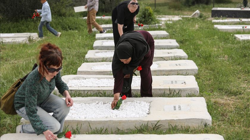 Pessoas colocam rosas nas campas durante a inauguração do cemitério na ilha de Lesbos, na Grécia. Foto: Reuters/Elias Marcou