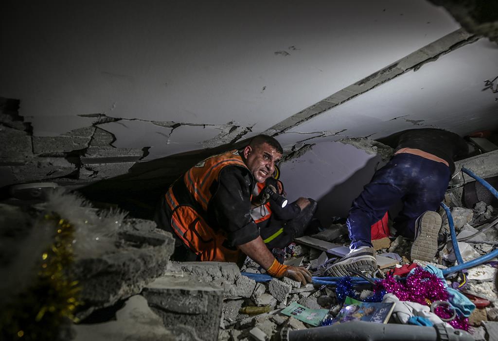 Elementos da Proteção Civil da Palestina procuram pessoas entre os escombros de um prédio destruído por Israel, em Gaza. Foto: Mohammed Saber/EPA