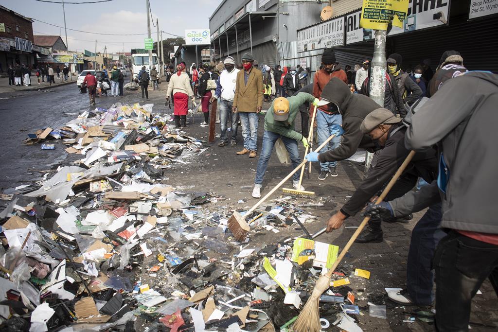 Moradores limpam rua após tumulto em Joanesburgo Foto: Kim Ludbrook/EPA