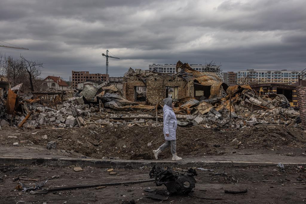 guerra na Ucrânia - mulher passa por casa destruída em Bucha Foto: Roman Pilipey/EPA