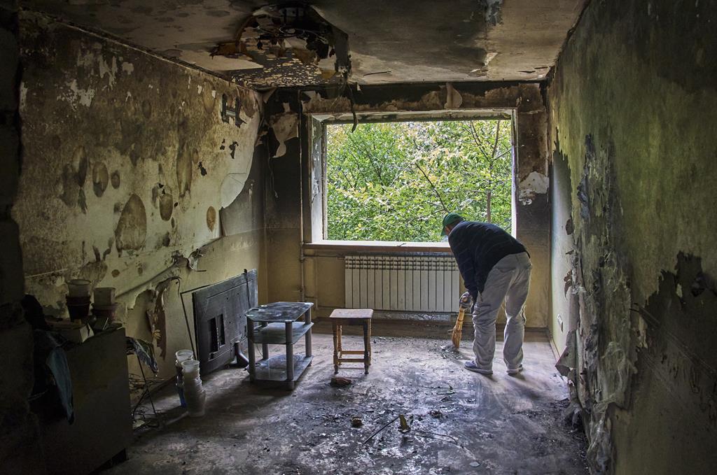 Homem limpa destroços da sua casa em Kharkiv. Foto: Sergey Kozlov/EPA