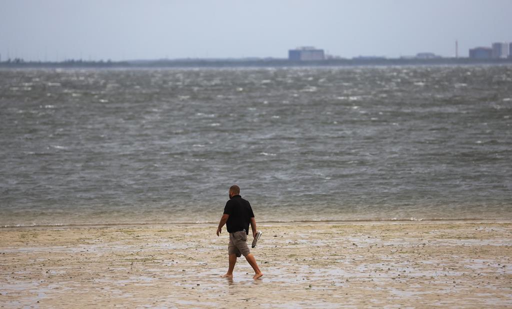 Homem caminha ao longo da costa da Florida atingida pelo furacão Ian. Foto: Tannen Maury/EPA