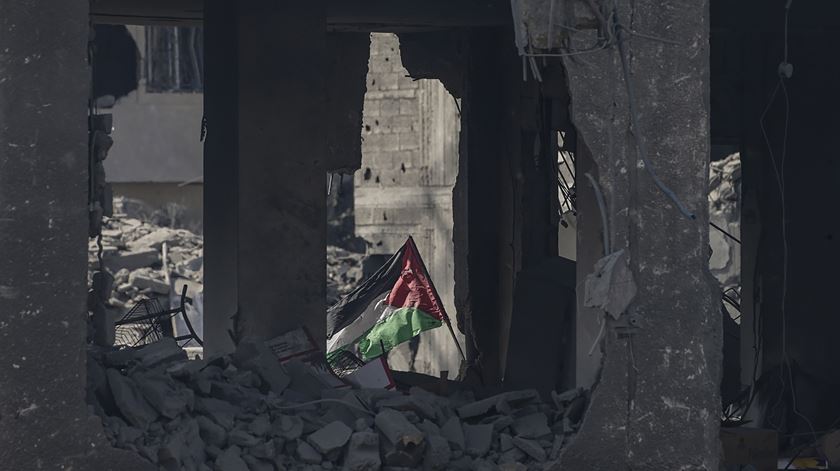 Após um ataque israelita em Gaza, uma bandeira palestiniana emerge no meio dos escombros. Foto: Mohammed Saber/EPA