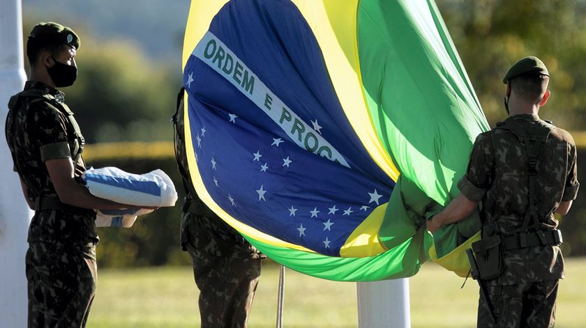 Militares com máscara descem a bandeira do Brasil. O país é dos que foi atingido com mais força pela pandemia. Foto: Joedson Alves/EPA