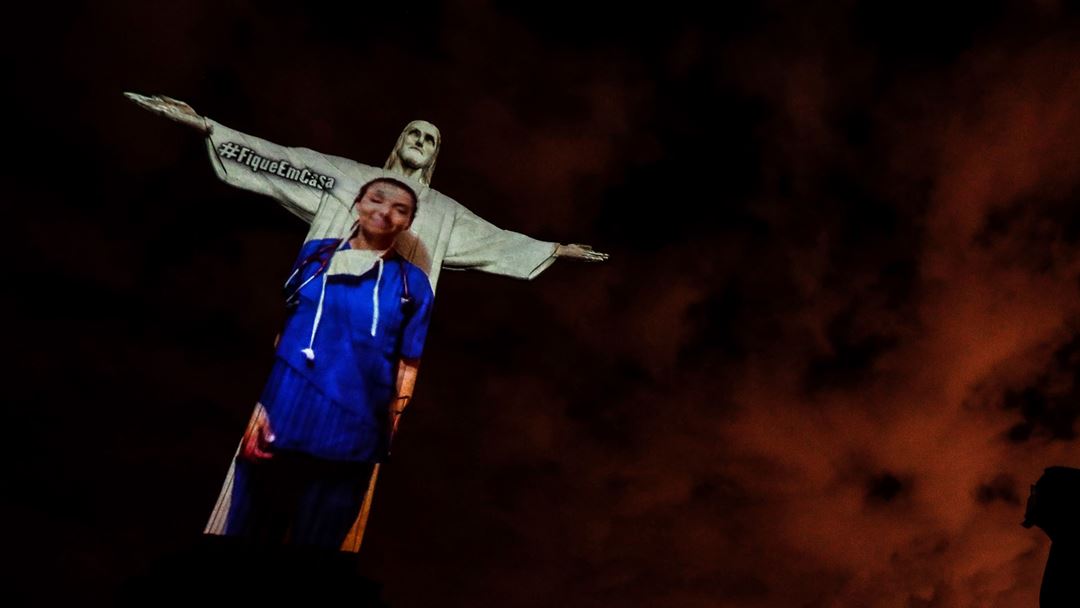Cristo-Redentor iluminado com a projeção de uma profissional de saúde durante o domingo de Páscoa, no Rio de Janeiro, Brasil. Foto: Antonio Lacerda/EPA