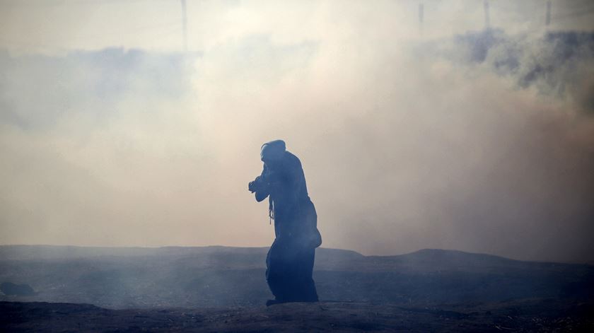 Palestiniana protege-se de gás lacrimogéneo lançado por Israel, na Faixa de Gaza. Foto: Mohammed Saber/Epa