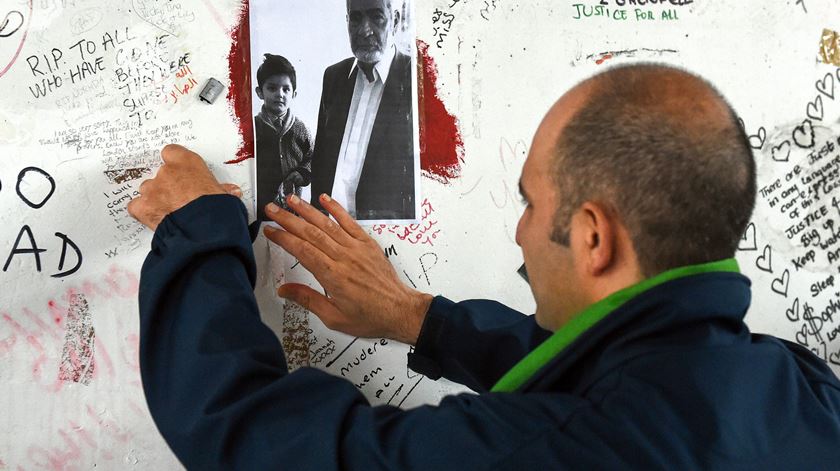 Hamid Ali Jafari coloca uma foto do seu  pai, Ali Yawar Jafari, na  parede de homenagem às vítimas  no  viaduto Westway. Foto: Neil Hall/ EPA
