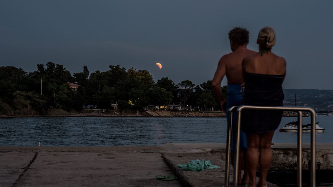 Veraneantes testemunham eclipse em Koper, Eslovénia, junto ao mar Adriático. Foto: Filip Singer/EPA