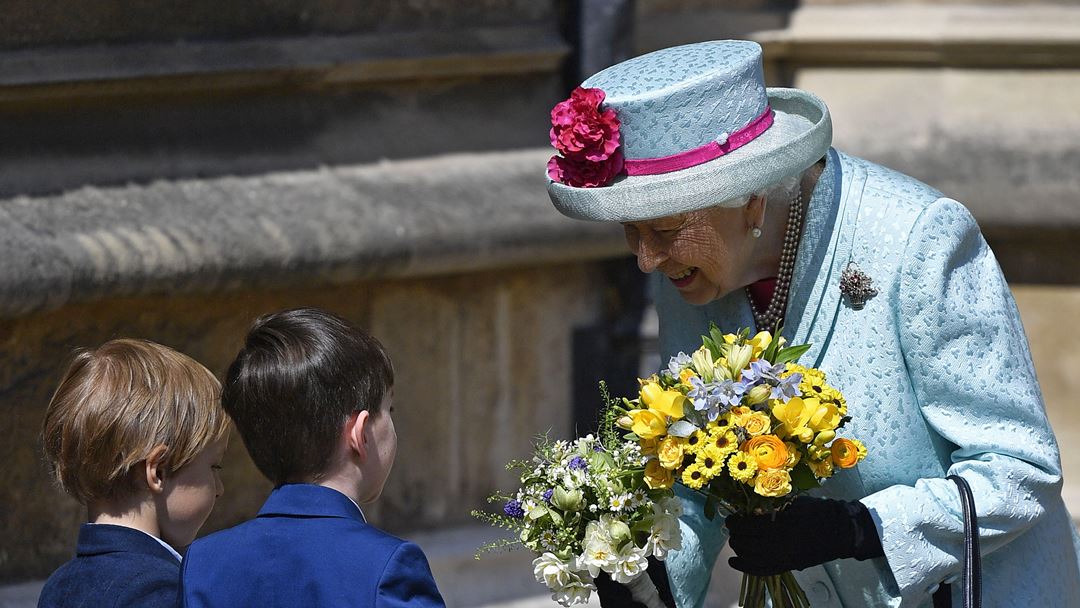À chegada à celebração, Isabel II recebeu dois ramos de flores entregues por duas crianças. Foto: Neil Hall/EPA