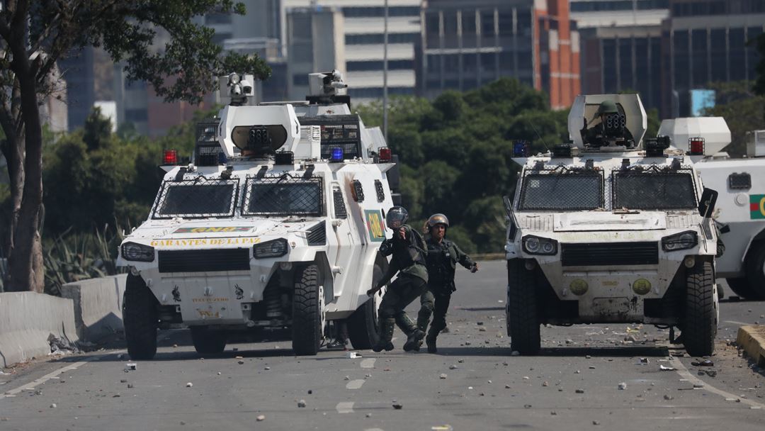 Carros blindados da Guarda Nacional Bolivariana impedem a passagem de apoiantes de Juan Guaidó, durante o protesto, numa das principais avenidas de Caracas, a Avenida Francisco de Miranda. Fotografia: Miguel Gutierrez/EPA