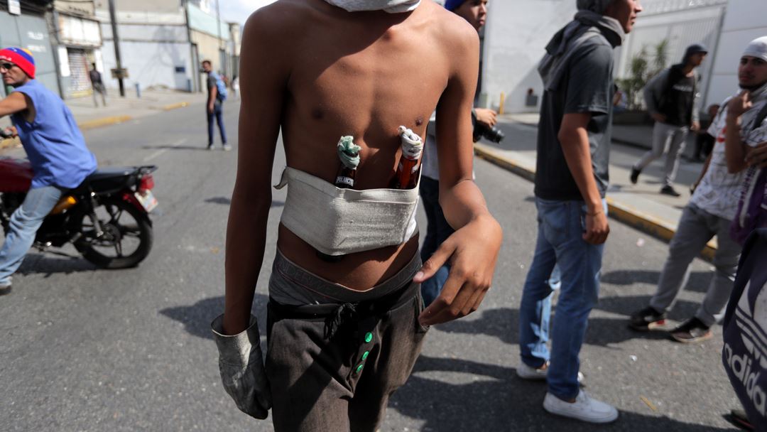 Garrafas de vidro com substâncias inflamáveis dentro servem de armas de arremesso aos manifestantes contra as forças do Governo.  Fotografias: Rayner Pena/EPA