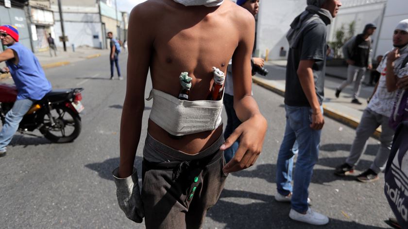 Garrafas de vidro com substâncias inflamáveis dentro servem de armas de arremesso aos manifestantes contra as forças do Governo.  Fotografias: Rayner Pena/EPA