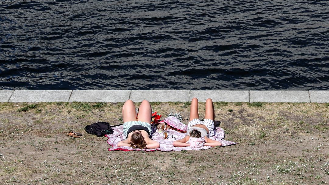 Locais refrescam-se junto ao rio Spree, em Berlim, na Alemanha. Foto: Julien de Rosa/EPA