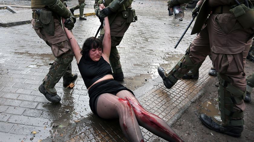 Uma ativista é arrastada pelo chão durante os protestos em Santiago, Chile. Foto: Elvis Gonzalez/EPA