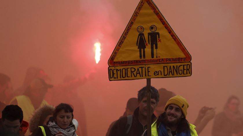 Manifestante com um cartaz de protesto com o aviso "democracia em perigo" na greve nacional em França. Foto: EPA/Guillaume Horcajuelo