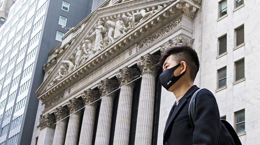 Homem usa máscara de proteção junto à Bolsa de Nova Iorque. Foto: Justin Lane/EPA
