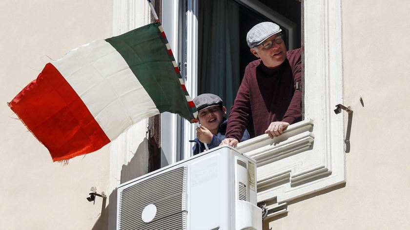 Residentes de Roma a celebrar o dia da liberdade à janela, sem esquecer a bandeira de Itália. Foto: Riccardo Antimiani/EPA