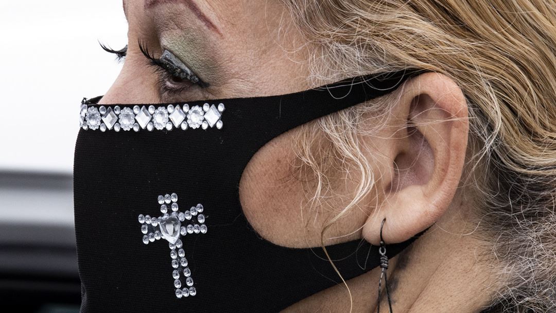 Mulher usa máscara decorada durante missa em formato "drive-in" em Norwalk, Los Angeles, EUA. Foto: Etienne/EPA