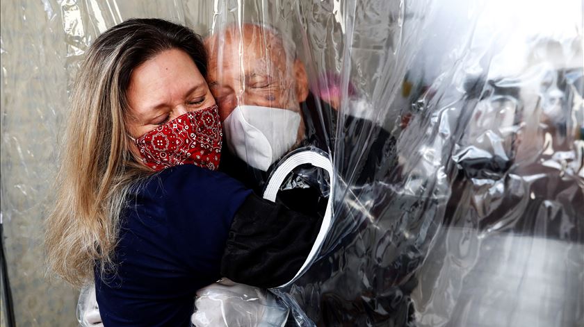 Uma filha abraça o pai através de uma cortina de plástico, por causa da pandemia. Foto: Sebastião Moreira/EPA