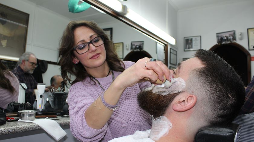 Halyna, a melhor barbeira do país, com um cliente a quem corta o cabelo desde os 13 anos. Foto: Liliana Carona/RR