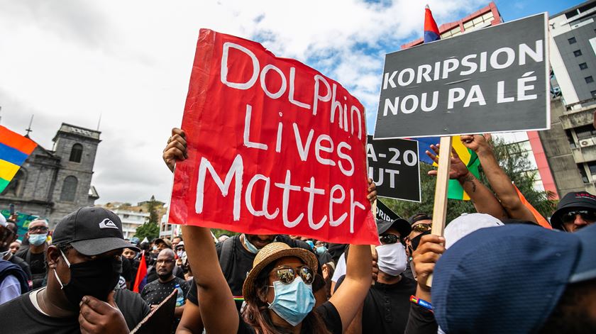 Manifestante com cartaz a pedir justiça pelos golfinhos que têm morrido nas águas das Maurícias após derrame de mil toneladas de petróleo no mar. Foto: Laura Morosoli/EPA