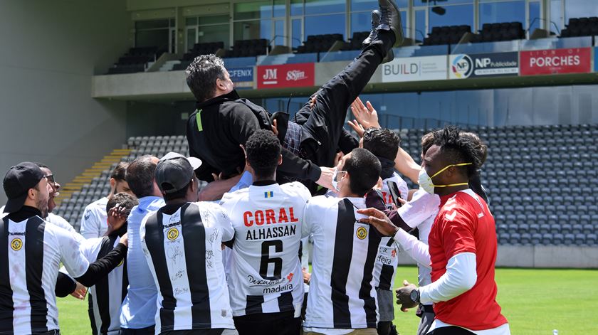 Jogadores e equipa técnica festejam subida no relvado. Foto: CD Nacional