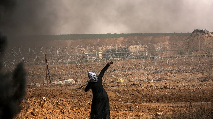 Palestiniana lanca pedras para o lado israelita da Fronteira. Foto: Mohammed Saber/EPA