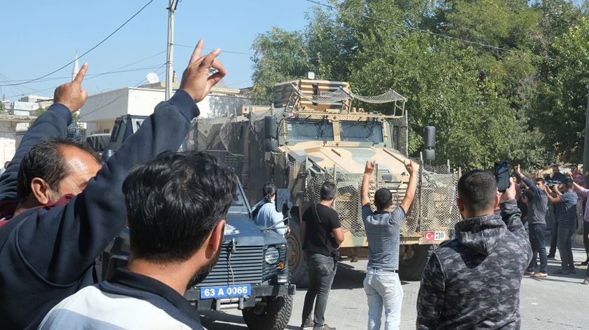 Turcos saudam a passagem de veiculos blindados a caminho da Síria. Foto: EPA